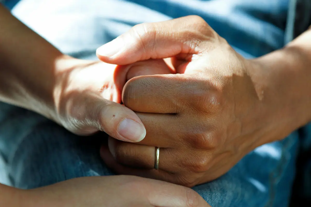 Two people's hands clasped together in support